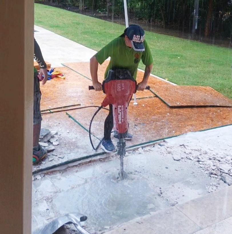 A JM Clean Care technician performs exterior demolition services with a jackhammer.