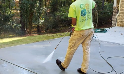 A JM Clean Care cleaning technician pressure washes a driveway.